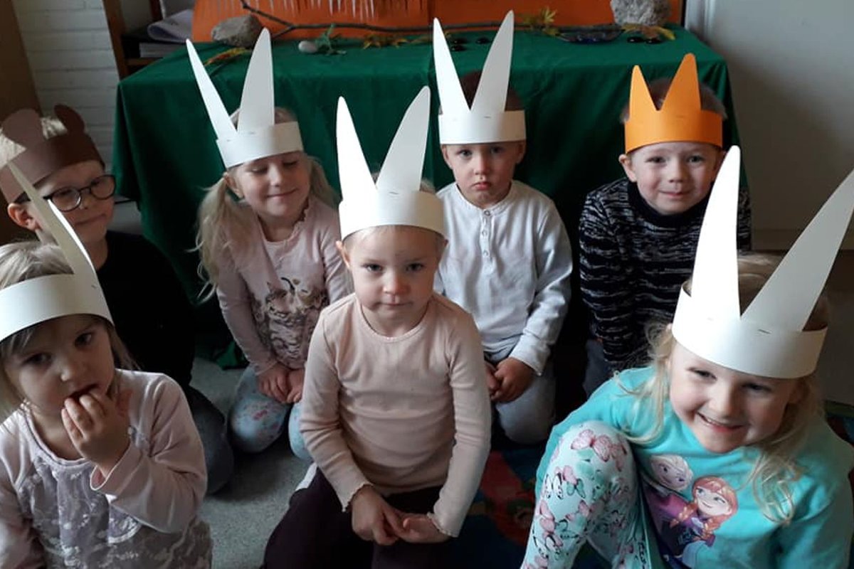 Lapset istuvat lattialla pupukorvat päässä.