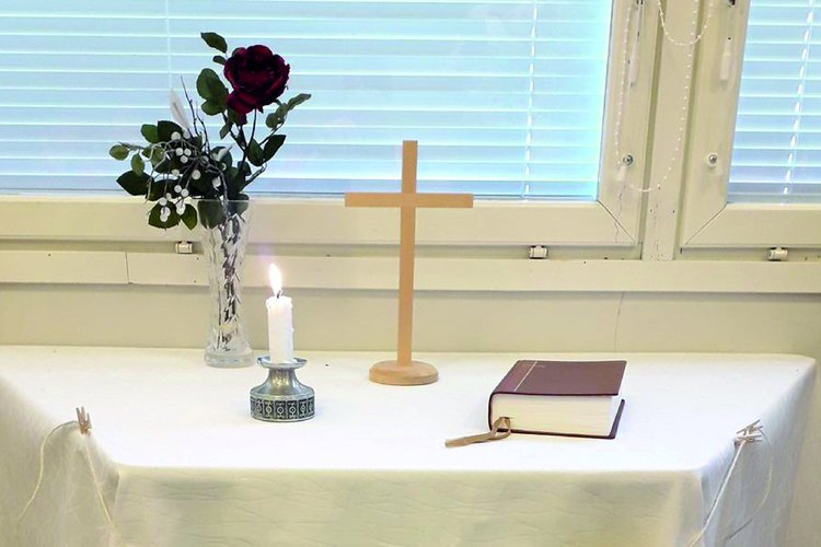 Pyhäkoulualttari, palava kynttilä, risti ja Raamattu.
